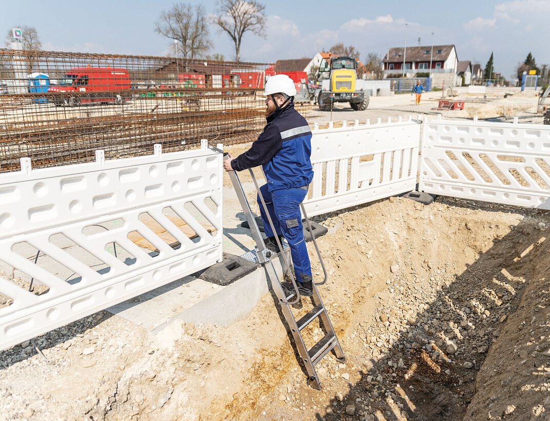 Ein hohes Maß an Sicherheit bietet die Stufen-Baugrubenleiter der Munk Günzburger Steigtechnik. Die extra breite, höhenverstellbare Plattform lässt sich am Baugrubenrand arretieren, beidseitige Handläufe bieten einen sicheren Halt. | © MUNK GmbH